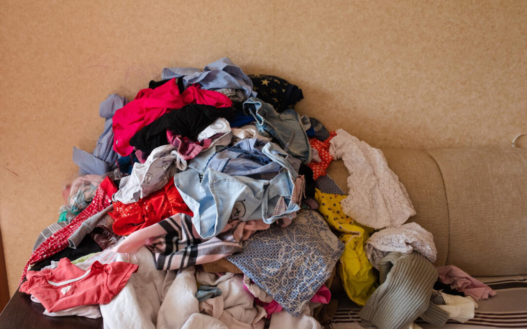 front view colorful childish clothes scattered sofa home big bunch clothes lying room before laundry concept cleaning mess mud household chores